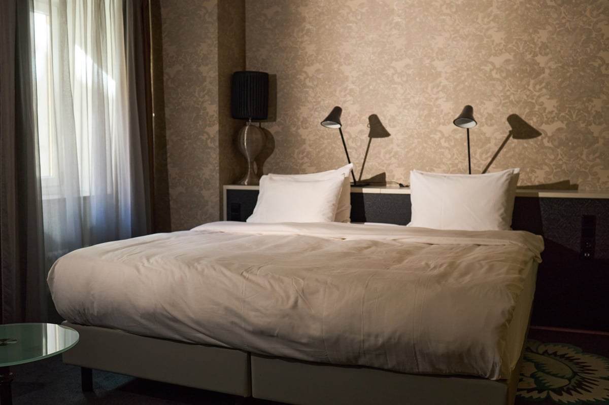 Wide angle view of luxury hotel bedroom featuring neatly made double bed and modern interior