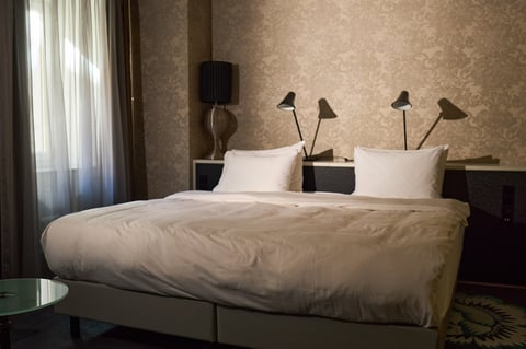 Wide angle view of luxury hotel bedroom featuring neatly made double bed and modern interior